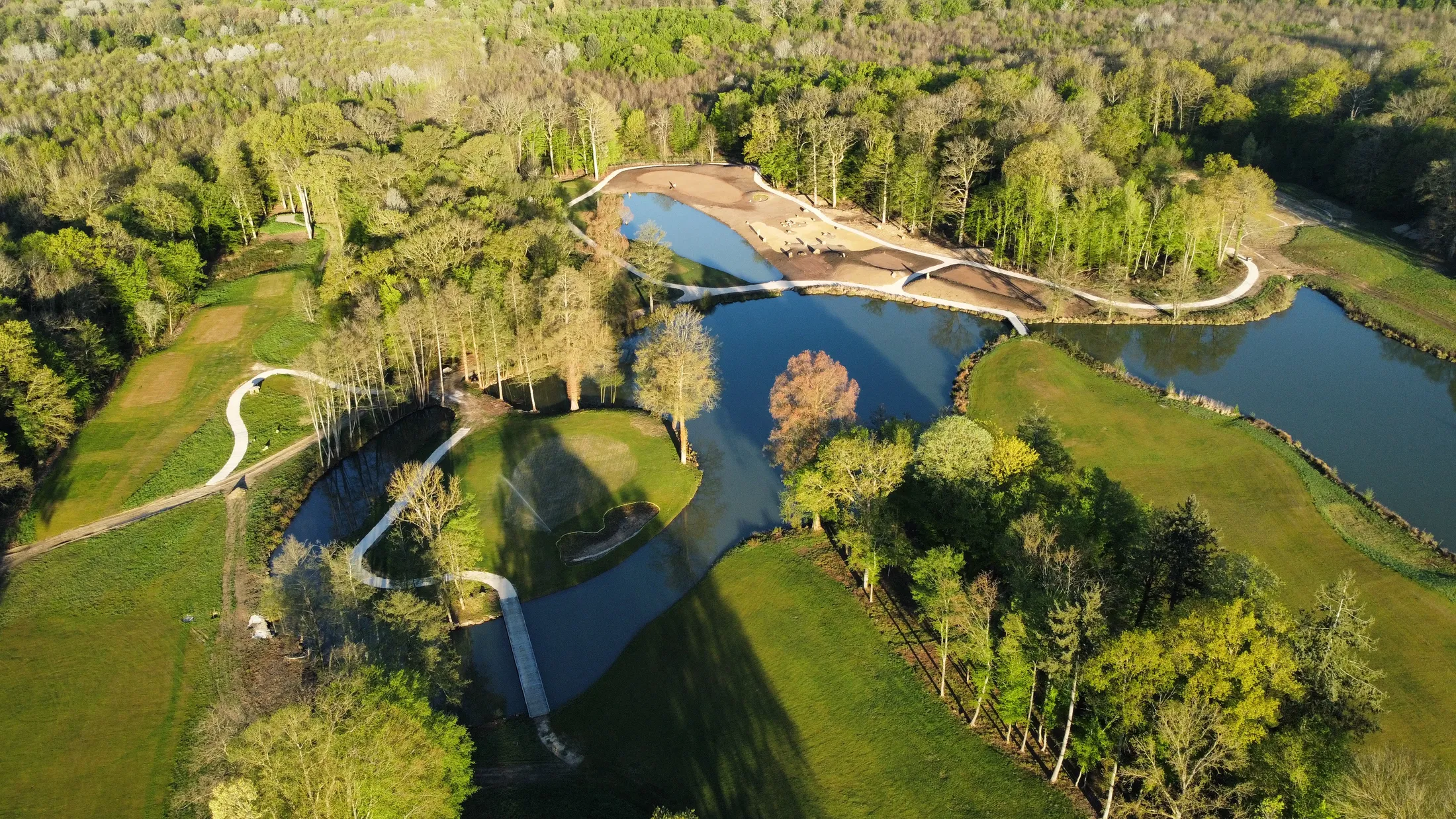 Vue aérienne du parcours 18 trous du Golf International Clément Ader, greens en île entourés d'eau et d'arbres centenaires